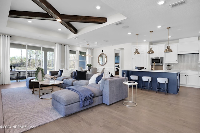 living room featuring coffered ceiling, beam ceiling, and light hardwood / wood-style flooring