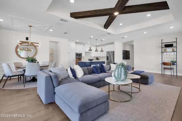 living room featuring beamed ceiling, light wood-type flooring, and a raised ceiling