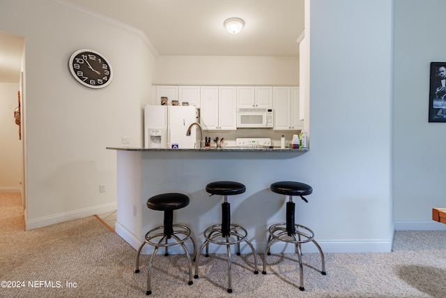 kitchen featuring white appliances, light carpet, kitchen peninsula, ornamental molding, and white cabinets