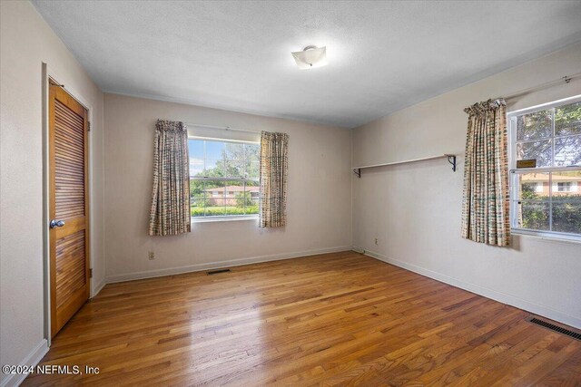 unfurnished bedroom with a closet, a textured ceiling, and hardwood / wood-style flooring