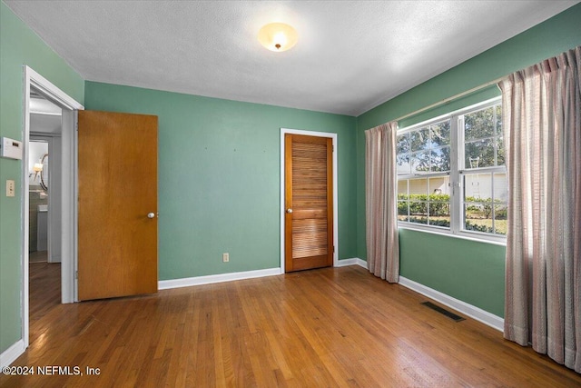 unfurnished bedroom featuring a closet, a textured ceiling, and wood-type flooring