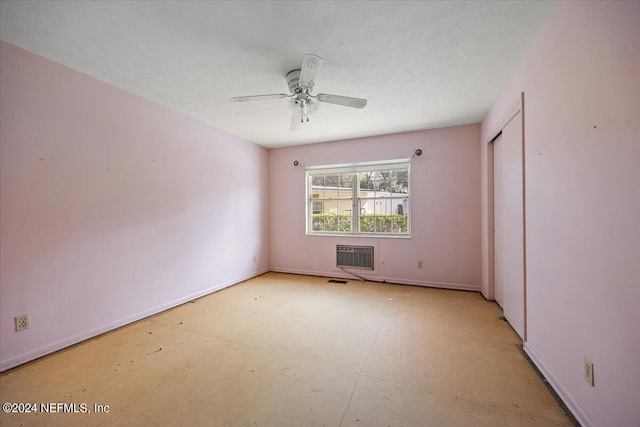 spare room with ceiling fan, a textured ceiling, and a wall mounted air conditioner