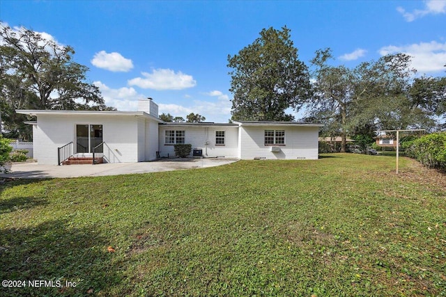 929 Bordeau Ave W, Jacksonville, FL 32211 - rear view of house featuring a patio, a lawn, concrete block siding, a chimney, and entry steps