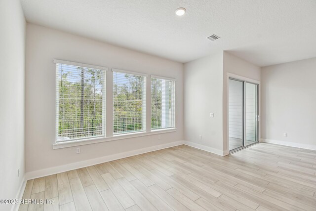 unfurnished room with visible vents, light wood finished floors, baseboards, and a healthy amount of sunlight