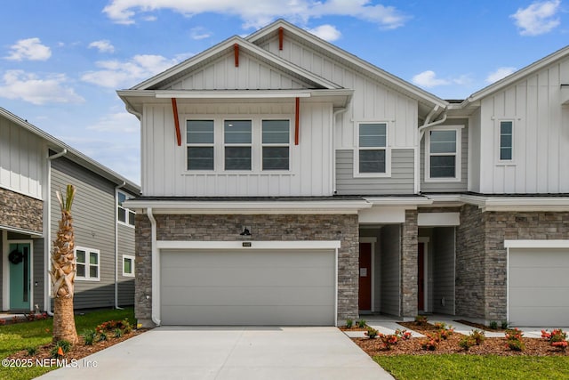 view of front of property with concrete driveway, board and batten siding, an attached garage, and stone siding