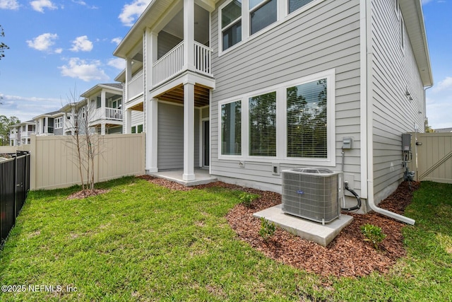 back of house with central air condition unit, fence, a lawn, and a balcony