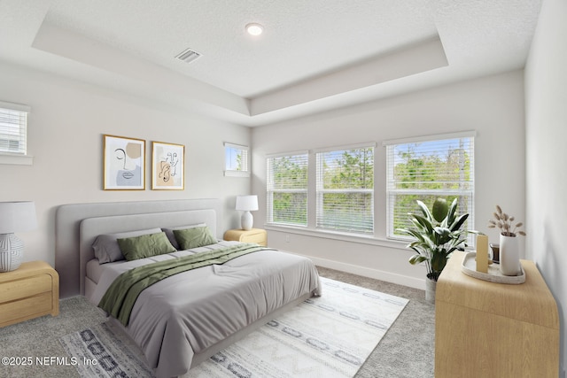 bedroom with visible vents, carpet flooring, baseboards, and a tray ceiling