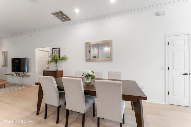 dining space with ornamental molding and light hardwood / wood-style floors