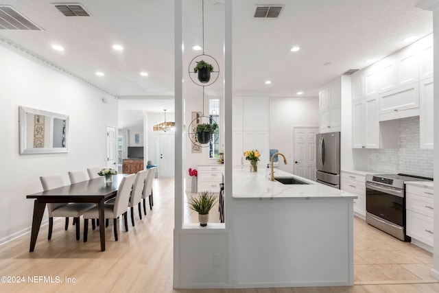 kitchen with appliances with stainless steel finishes, light stone counters, white cabinets, backsplash, and sink