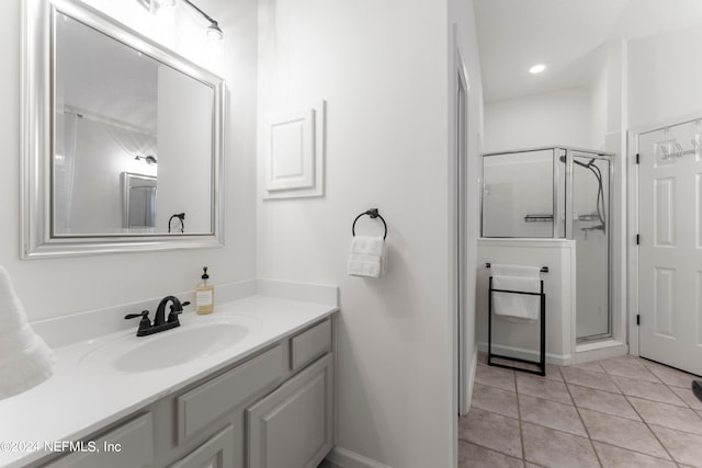 bathroom featuring a shower with door, vanity, and tile patterned floors