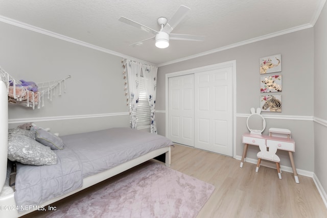 bedroom featuring a closet, ceiling fan, ornamental molding, a textured ceiling, and light hardwood / wood-style flooring