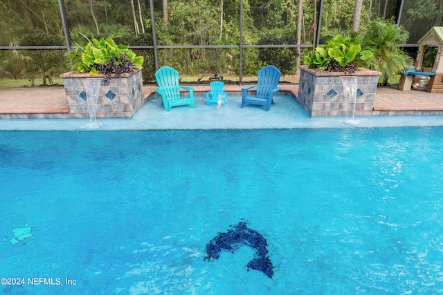 view of swimming pool featuring pool water feature, a lanai, and a patio