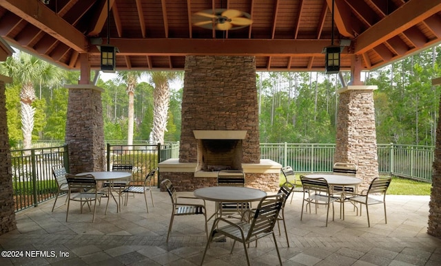 view of patio / terrace with a gazebo, ceiling fan, and an outdoor stone fireplace