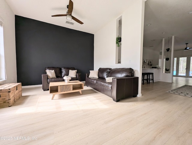 living room with lofted ceiling, ceiling fan, and light wood-type flooring