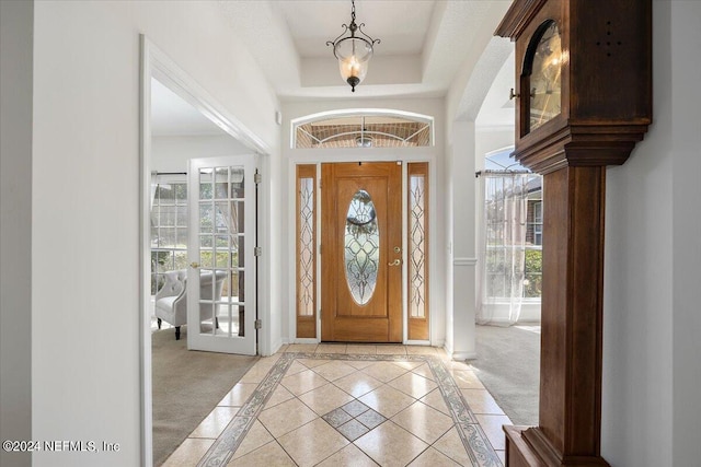 carpeted foyer entrance with a tray ceiling