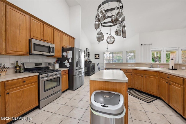 kitchen featuring a towering ceiling, a healthy amount of sunlight, a center island, and stainless steel appliances