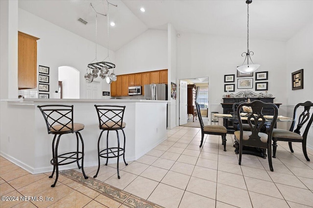 kitchen with pendant lighting, kitchen peninsula, high vaulted ceiling, stainless steel appliances, and an inviting chandelier