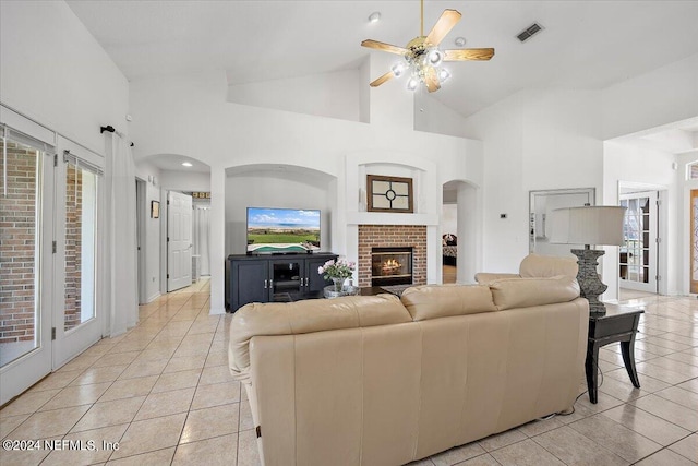 living room with high vaulted ceiling, ceiling fan, a fireplace, and light tile patterned floors