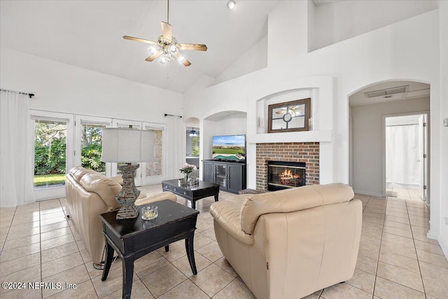 living room with light tile patterned flooring, high vaulted ceiling, a fireplace, and ceiling fan