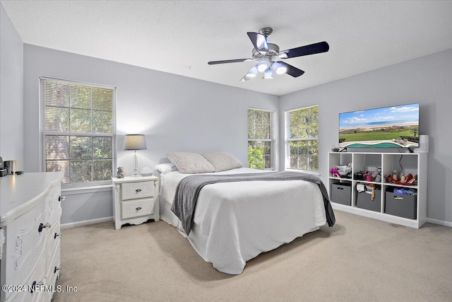 carpeted bedroom with ceiling fan and a textured ceiling