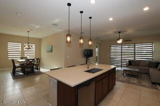 kitchen featuring hanging light fixtures, sink, an island with sink, and a wealth of natural light