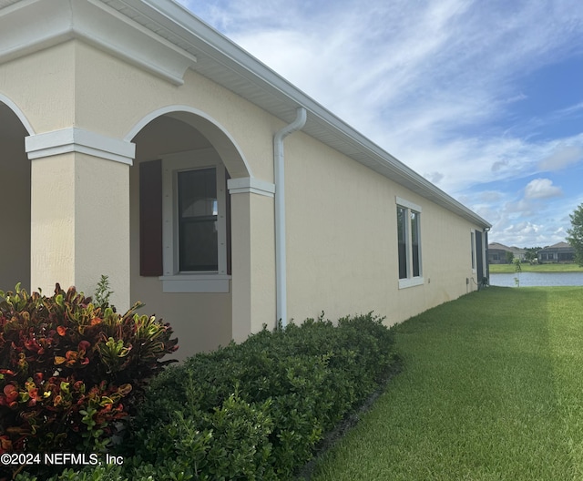 view of property exterior featuring a yard and a water view