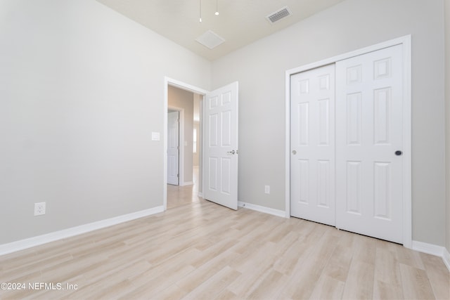 unfurnished bedroom with light hardwood / wood-style flooring and a closet