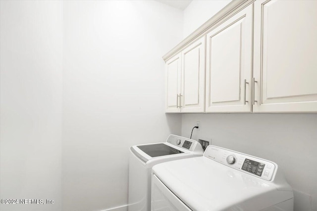 clothes washing area with washer and clothes dryer and cabinets