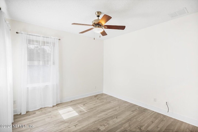 empty room with a textured ceiling, light hardwood / wood-style floors, and ceiling fan