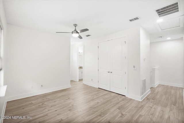 unfurnished bedroom with a closet, ensuite bathroom, light wood-type flooring, and ceiling fan