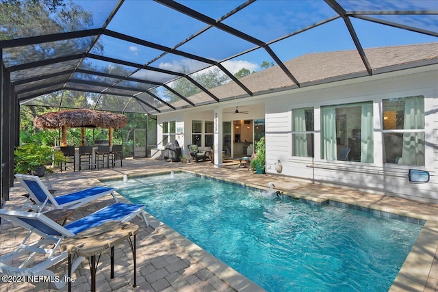 view of pool featuring pool water feature, ceiling fan, a patio, and a lanai