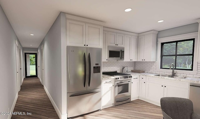 kitchen with appliances with stainless steel finishes, light wood-type flooring, sink, and white cabinetry