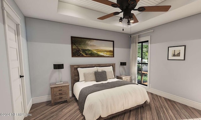 bedroom with a tray ceiling, ceiling fan, and hardwood / wood-style flooring