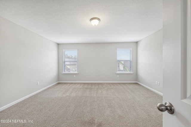 unfurnished room featuring light colored carpet and a textured ceiling