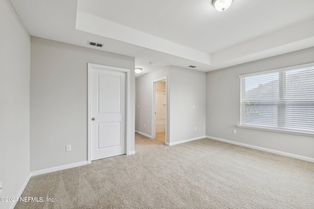 carpeted empty room featuring a tray ceiling