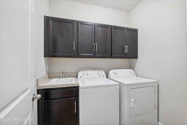 clothes washing area featuring separate washer and dryer, sink, and cabinets