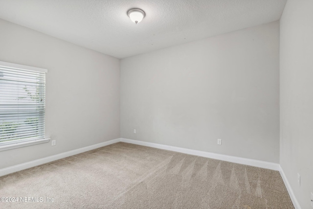 carpeted empty room featuring a textured ceiling