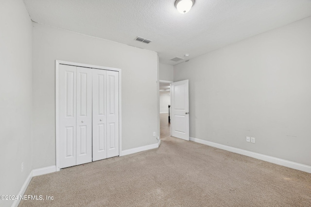 unfurnished bedroom featuring a closet, carpet flooring, and a textured ceiling