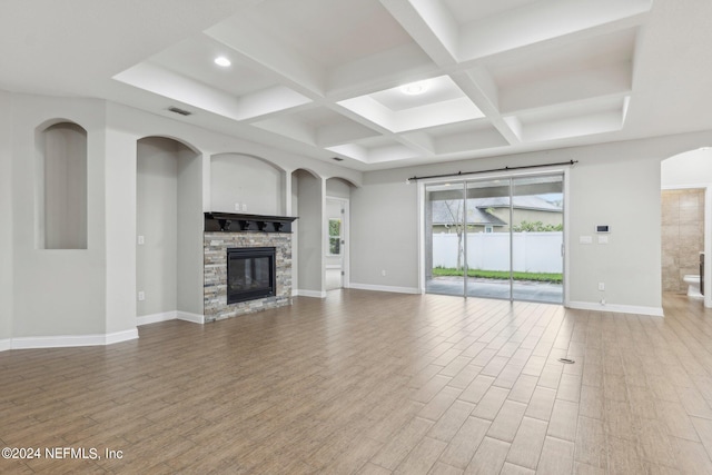 unfurnished living room featuring wood-type flooring, a fireplace, coffered ceiling, and beam ceiling