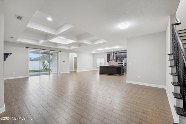 unfurnished living room with coffered ceiling, beamed ceiling, a textured ceiling, and hardwood / wood-style floors