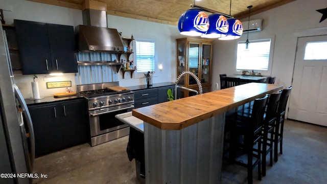 kitchen featuring pendant lighting, stainless steel appliances, a kitchen breakfast bar, and wall chimney exhaust hood