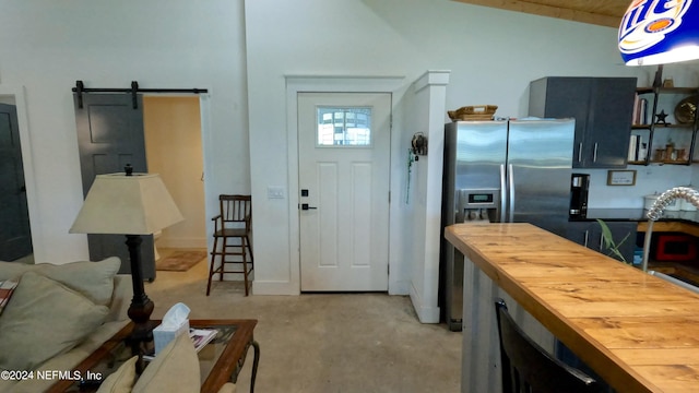 kitchen with lofted ceiling, wooden counters, stainless steel fridge with ice dispenser, light carpet, and a barn door