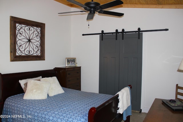 bedroom featuring lofted ceiling with beams, a closet, ceiling fan, and a barn door