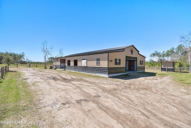17667 Andrews Rd, Hilliard, FL 32046 - view of front of house with an outdoor structure, a detached garage, fence, and dirt driveway