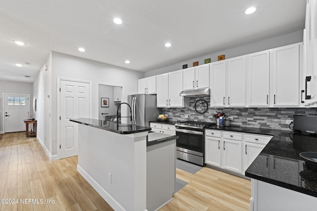 kitchen with white cabinetry, light wood-type flooring, appliances with stainless steel finishes, a kitchen island with sink, and backsplash