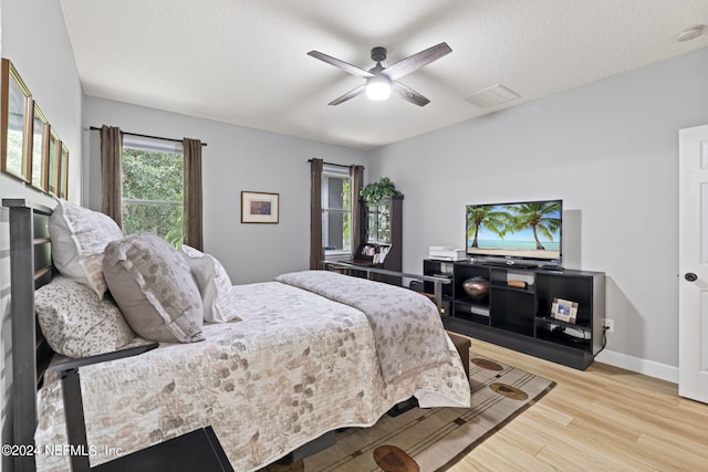 bedroom with ceiling fan, a textured ceiling, and light wood-type flooring