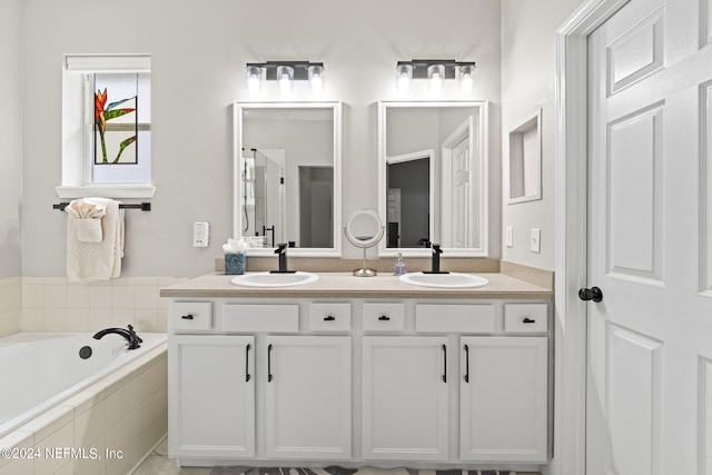 bathroom with vanity and tiled bath