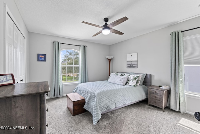 bedroom with ceiling fan, light colored carpet, a closet, and a textured ceiling