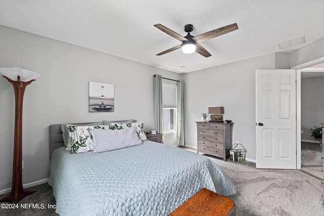 carpeted bedroom featuring ceiling fan and a textured ceiling