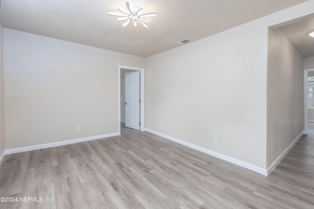 empty room with light wood-type flooring and an inviting chandelier